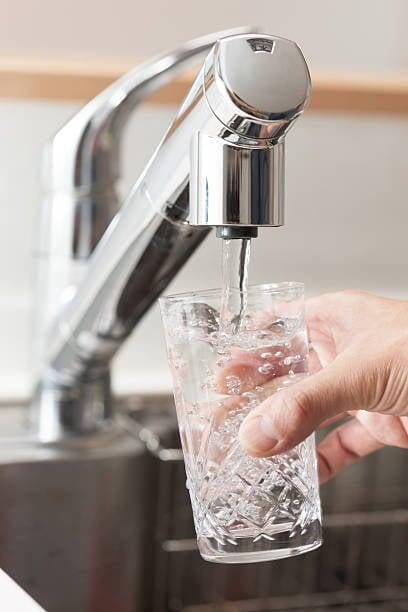 A person pouring water from a filtered tap