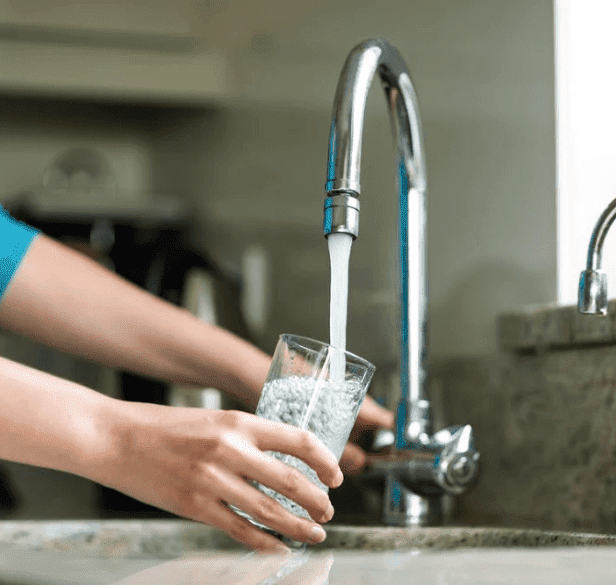 A person pouring filtered drinking water into a glass