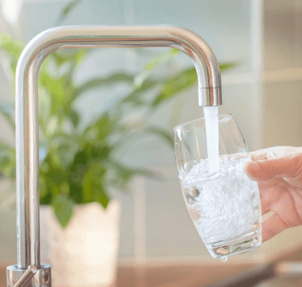 A person filling a glass with filtered drinking water