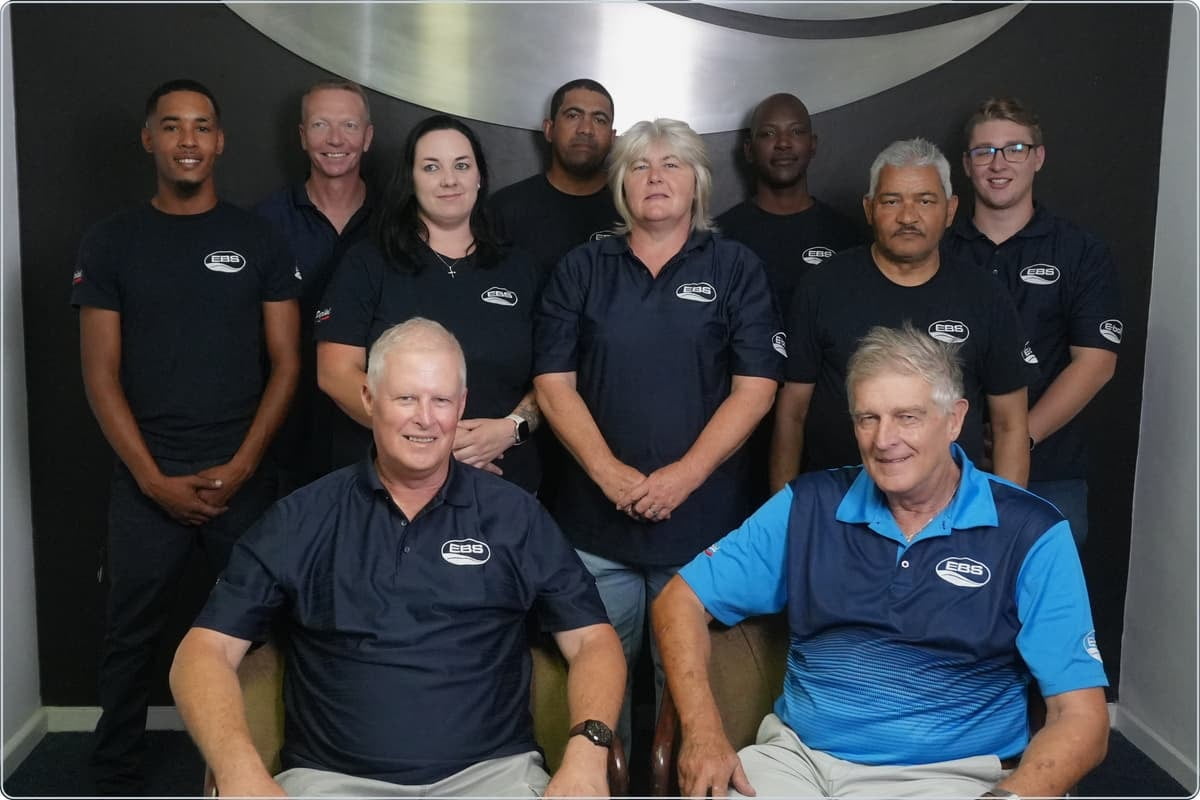 The E-Boil Systems team in branded shirts in front of the EBS wave logo at their Cape Town premises