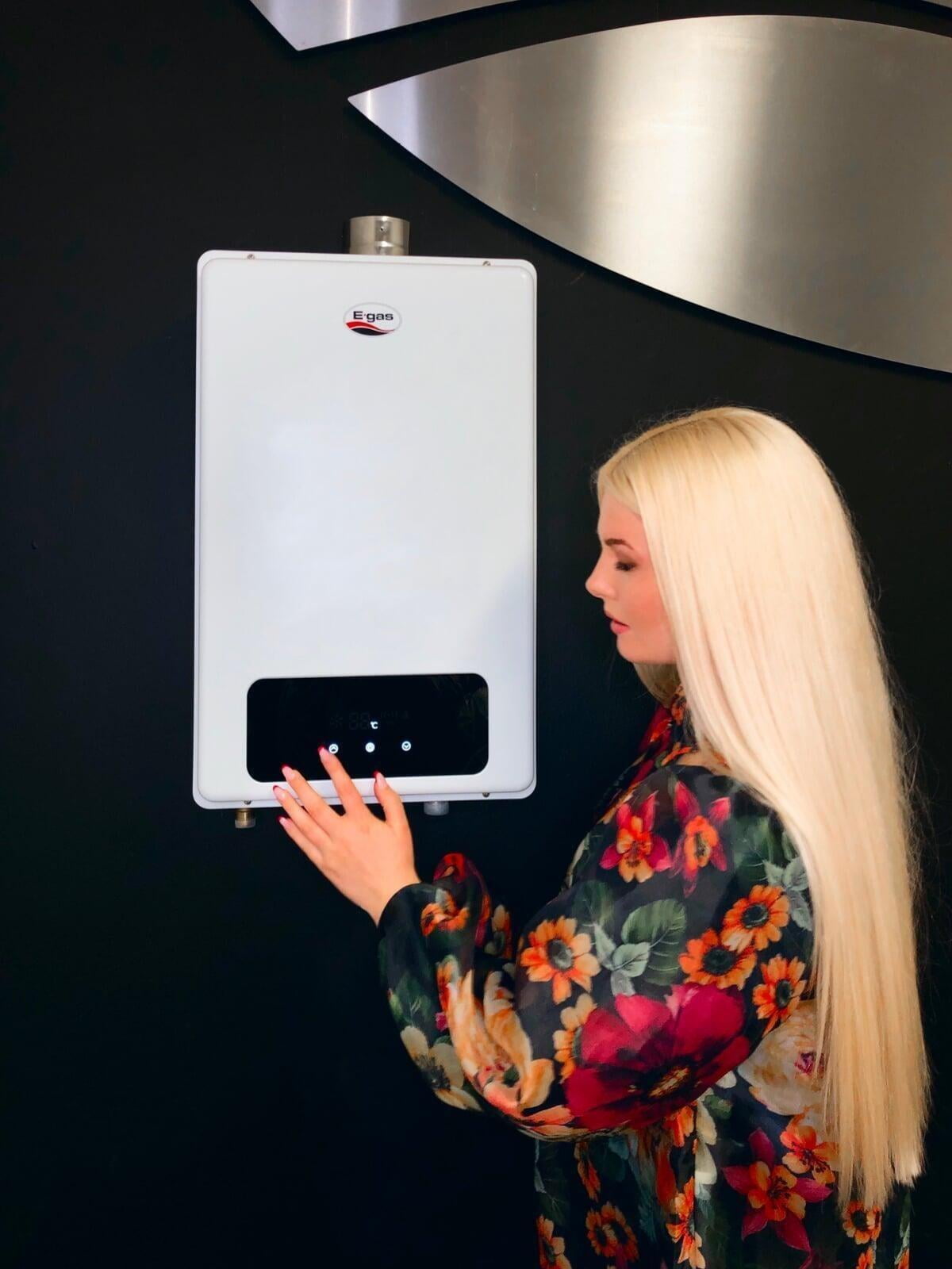 A woman adjusting the touch-screen display on the e-gas geyser