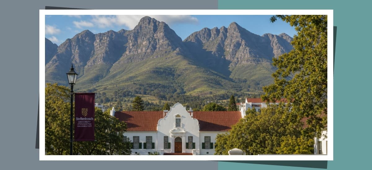 Stellenbosch University campus building framed by green trees and towering mountains